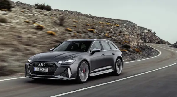 Szary Audi RS6 Avant pędzi po krętej drodze wśród skalistych wzgórz.