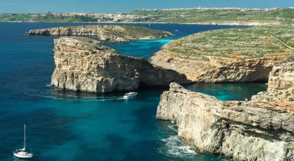 Malta w lutym: rejs łodzią po turkusowych wodach, skaliste wybrzeża i widok na miasto w oddali. Idealne miejsce na odkrywanie!