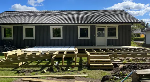 Grundarbete för att bygga veranda. Träkonstruktion och trappor på plats framför huset.