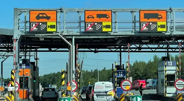 Bramki A4 z wyświetlaczami informującymi o typie pojazdu i opłatach. Samochody i ciężarówki zbliżają się do punktów poboru opłat.