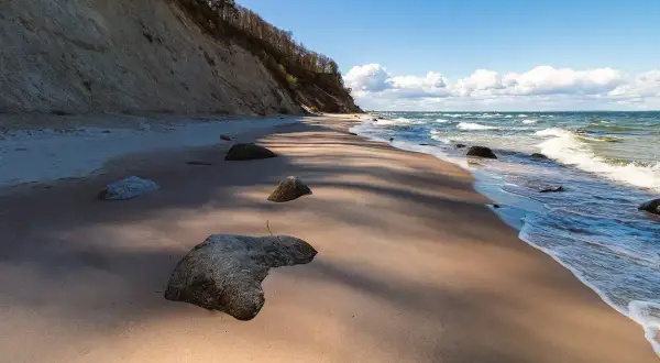 Plaża z klifem i kamieniami, fale Bałtyku. Wyobraź sobie, że to jedne z **polskich wysp na Bałtyku**, gdzie natura tworzy dzikie krajobrazy.