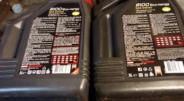 Dwie czarne butelki oleju silnikowego Motul 8100 Eco-nergy SAE 5W30 z etykietami w języku polskim i angielskim.