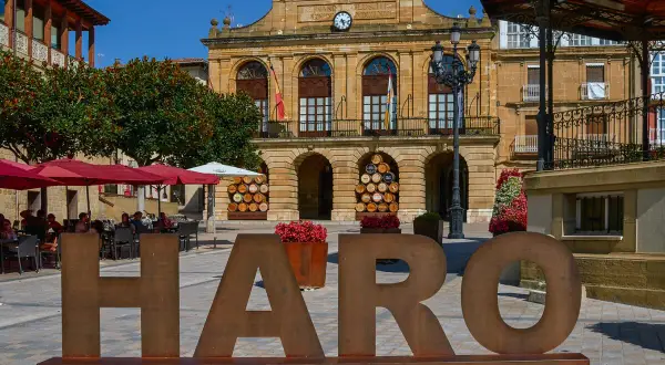 Letras gigantes "HARO CAPITAL DEL RIOJA" en plaza con Ayuntamiento y terraza. Descubre qué ver en Haro.