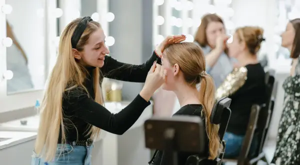 Uczestniczki szkoleń beauty ćwiczą makijaż przy lustrach z oświetleniem.