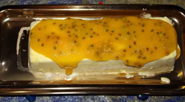 Gâteau glacé rectangulaire nappé d'un confit mangue passion aux graines visibles, sur un plateau doré.
