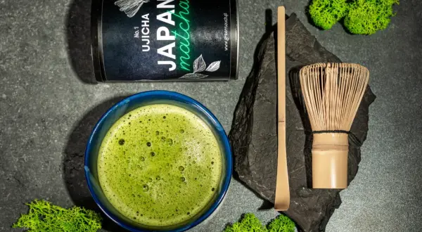 Zestaw do parzenia matcha: puszka z zieloną herbatą, spieniony napój w miseczce, bambusowa miotełka (chasen) i łopatka (chashaku).