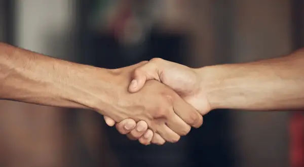 Dwie dłonie złączone w uścisku, symbolizujące porozumienie i znak pokoju.
