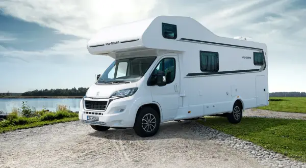 Biały kamper Weinsberg zaparkowany nad jeziorem, gotowy na przygodę. Ten camper to wolność podróżowania.