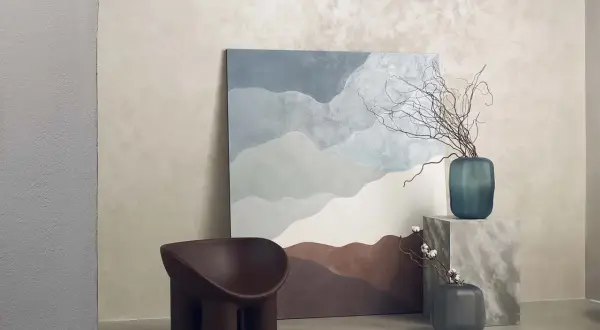 Parete con finitura materica, un quadro astratto e una poltrona dal design organico. La **decorative paint** crea un'atmosfera rilassante.