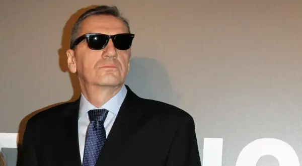 Władysław Pasikowski w czarnym garniturze i okularach przeciwsłonecznych, gotowy na premierę swojego kolejnego filmu.
