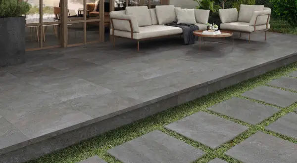 Terraza moderna con suelo de baldosas grises, ideal para pintar y renovar tu espacio exterior. Muebles de exterior y plantas verdes.