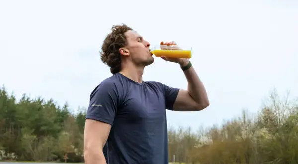 Sportler trinkt nach dem Training ein Getränk. Wann Elektrolyte nehmen? Nach dem Sport ist die beste Zeit.