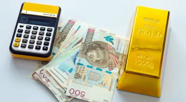 Kalkulator, polskie banknoty 500 zł i sztabka złota 1000g. Zastanawiasz się, ile kosztuje 1 uncja złota?