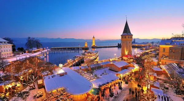 Winterzauber am Hafenweihnacht Lindau: Lichterglanz, Schnee und Menschenmassen vor dem alten Wasserturm und den Leuchttürmen.