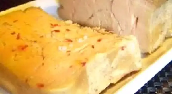 Deux blocs de foie gras sur une assiette blanche. L'un est parsemé de sel et de piment rouge, prêt pour une recette de foie gras au sel sans cuisson.