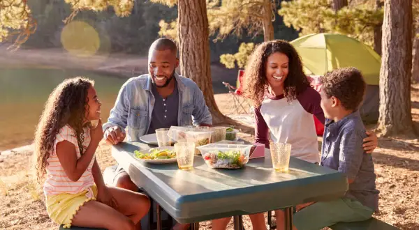 Familia disfrutando un picnic junto a un lago, una escena perfecta de qué hacer en familia al aire libre.