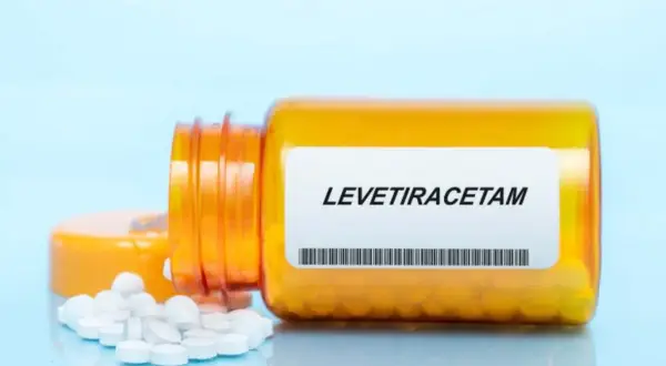 Pomarańczowa butelka z lekiem levetiracetam, z której wysypały się białe tabletki.