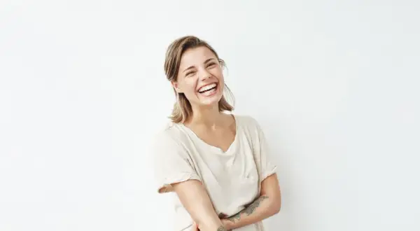 Lachende Frau mit Tattoo am Arm, die sich freut, weil sie nicht mehr single sein will und auf den Richtigen wartet.