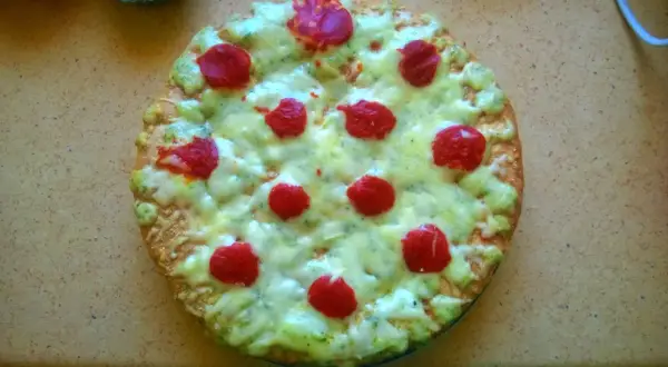 Domowa pizza z serem, zielonym sosem i czerwonymi kółkami pepperoni.