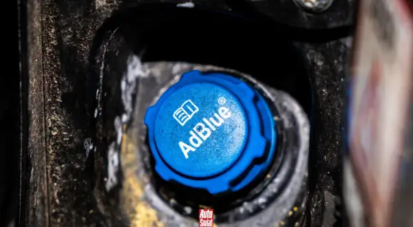 Niebieski korek wlewu AdBlue, z napisem "AdBlue" i symbolem książki. Czy adblue zamarza? To pytanie nurtuje wielu kierowców zimą.