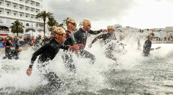 Sportler stürmen ins Wasser für einen Triathlon Kurzdistanz.