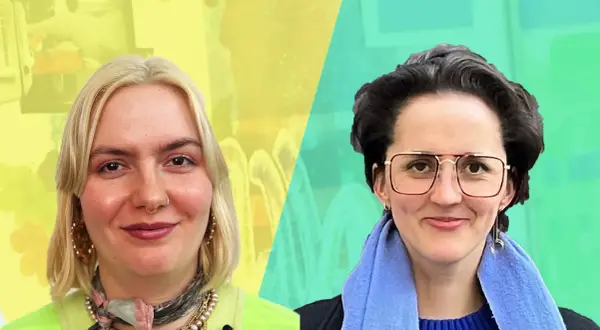 Zwei Frauen lächeln, eine mit blonden Haaren, die andere mit dunklen Haaren und Brille. Sie könnten sich für ein Grafik Design Studium in Berlin bewerben.