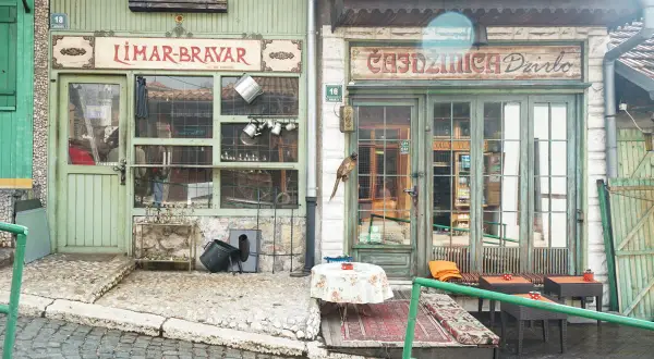 Faszinierende Szene in der Sarajevo Altstadt: Ein Vogel sitzt auf einem Geschäftsschild, davor ein Tisch mit Blumen.