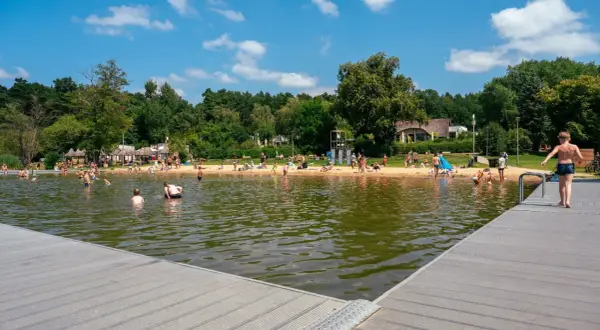 Słoneczny dzień na kąpieliskach w Poznaniu. Ludzie kąpią się, opalają na plaży i odpoczywają nad wodą.
