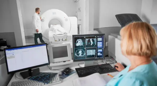 Lekarz nadzoruje badanie tomografem komputerowym, podczas gdy technik analizuje obrazy na monitorze. Czy tomografia komputerowa wykryje raka?