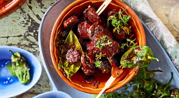 Leckeres Tapas Fingerfood: Glasierte Datteln mit Kräutern und geröstete Pimientos de Padrón.