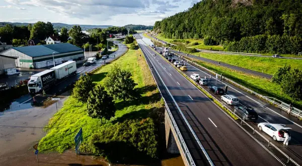 Trafikkaos vid en översvämmad rastplats. Bilar står stilla på motorvägen, en lastbil har fastnat i vattnet.
