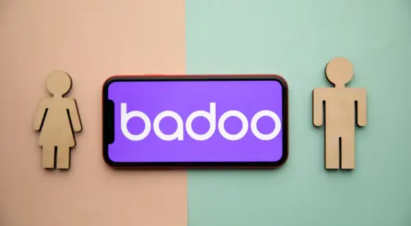 Drewniane figurki kobiety i mężczyzny po bokach telefonu z logo Badoo. Czy to portal randkowy?