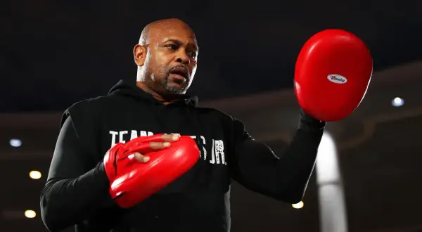 Roy Jones Jr. sweats during training, preparing for one of his best fights. He holds red boxing pads, ready to train.
