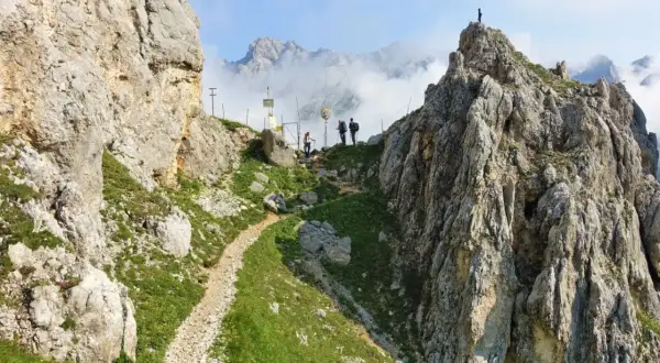 Wanderer auf der Gatterl Tour zur Zugspitze genießen den Ausblick auf felsige Gipfel und Wolkenmeere.