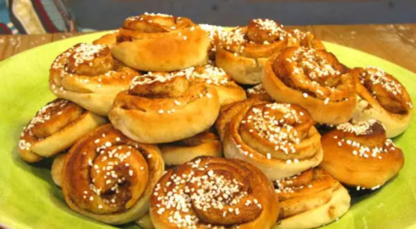 En hög med nybakade kanelbullar, perfekta att baka med mycket mjölk för extra saftighet. Strösslade med pärlsocker.