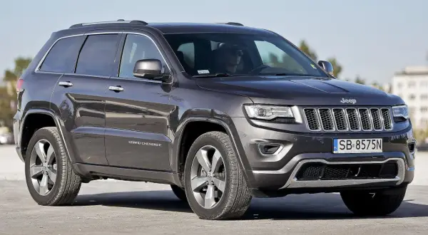 Ciemnoszary Jeep Grand Cherokee WK2 z polskimi tablicami SB 8575N zaparkowany na zewnątrz.