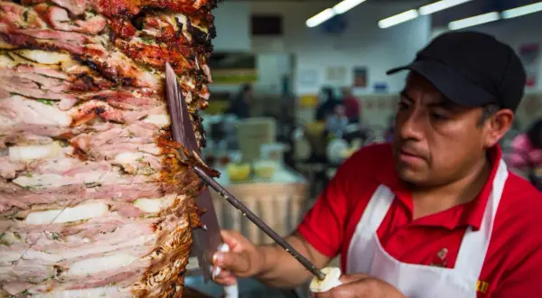 Kucharz kroi obracający się pionowo kebab z warstw mięsa i cebuli.