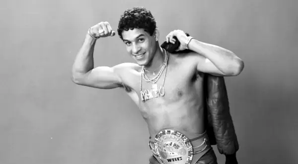 Boxaren Hector Camacho poserar stolt med sitt WBC-mästarbälte och en läderjacka över axeln.