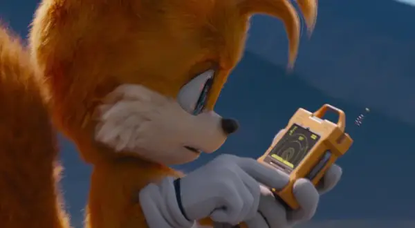 Tails Sonic, z dwoma ogonami, analizuje dane na żółtym urządzeniu.