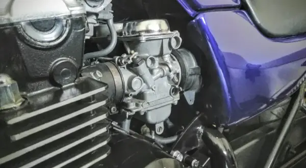 Fragment motocykla z widocznym gaźnikiem i elementami silnika.