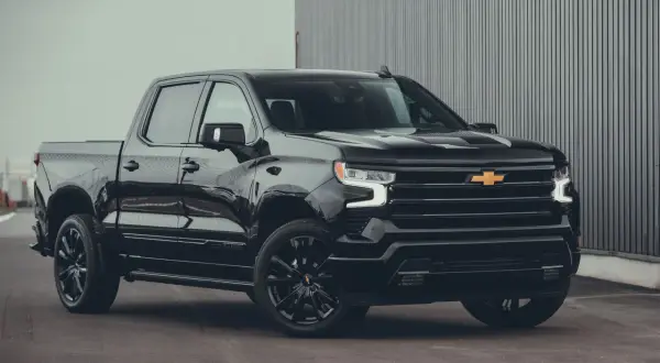 Svart Chevrolet Silverado High Country, en av många imponerande Chevrolet modeller, parkerad framför en modern byggnad.