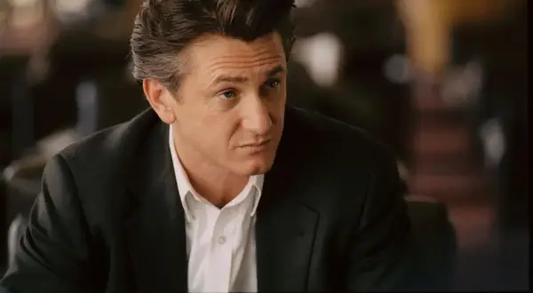 Sean Penn w czarnym garniturze i białej koszuli, wygląda jakby zastanawiał się nad kolejną rolą w swoich filmach.