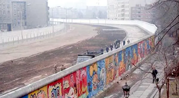 Kolorowy Mur Berliński, świadectwo czasów, kiedy wzniesiono mur berliński, z ludźmi spacerującymi po chodniku.