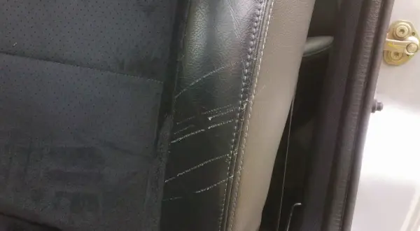 Siège de voiture en cuir noir avec des éraflures visibles, nécessitant une réparation de griffure cuir.