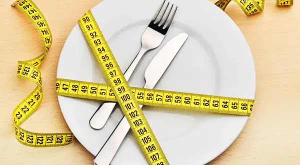 Une assiette avec couverts est entourée d'un mètre ruban jaune. La question "quel poids pour 1m60 femme" est implicite.