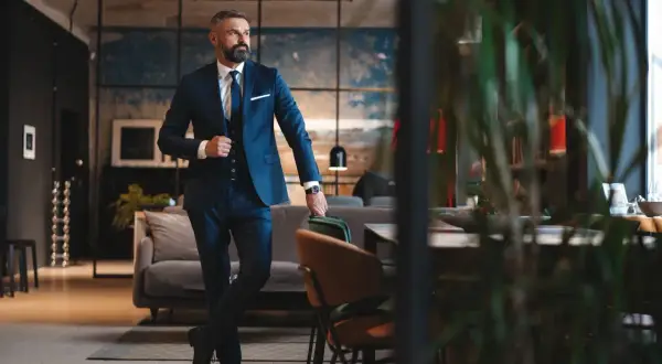 Ein Mann im eleganten dunkelblauen Lounge Suit steht lässig in einem stilvollen Loft.