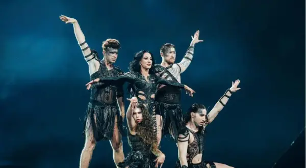 Artyści w czarnych strojach z frędzlami tańczą na scenie Eurowizji.