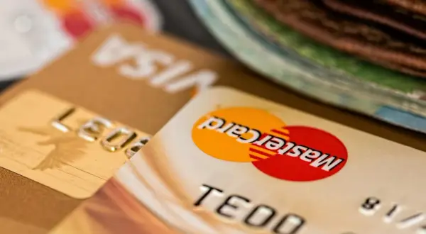Zbliżenie na karty płatnicze Visa i Mastercard, z widocznym numerem karty i logo. Może to oznaczać debet na karcie lub po prostu jej posiadanie.