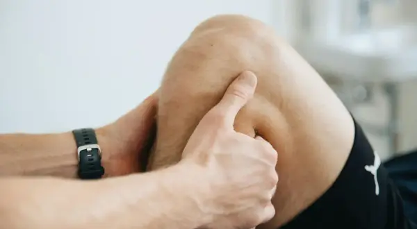Un kinésithérapeute examine le creux poplité d'un patient, peut-être pour diagnostiquer une douleur ou une blessure.