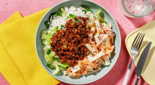 En skål med ris, grönsaker och en kryddig topping. Ett gott kålrabbi recept som ser aptitligt ut.